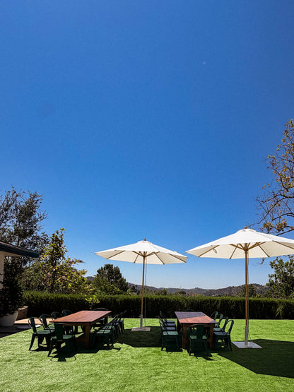 Two Fossil White Bamboo Umbrellas shading dining tables and chairs on a backyard lawn for an outdoor event in Calabasas, CA.